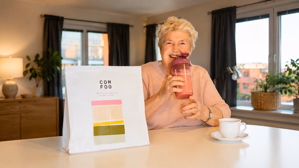 Britt, 83, dricker ComFoo hemma vid köksbordet med en ComFoo-påse bredvid sig